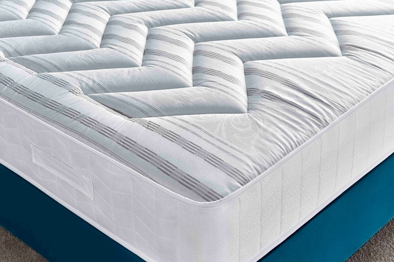 Close-up of Deep Sleep Deluxe Orthocare mattress with a white cover on a blue base.