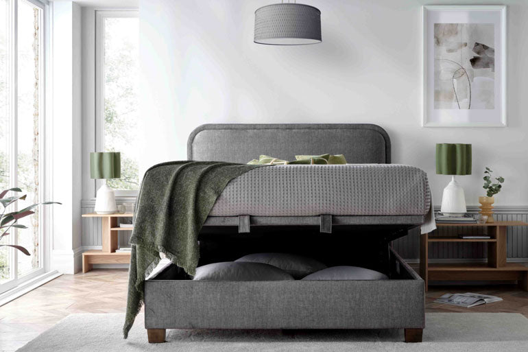Kaydian Clifton Ottoman Bed in Vogue Grey with storage compartment partly open in bedroom setting.