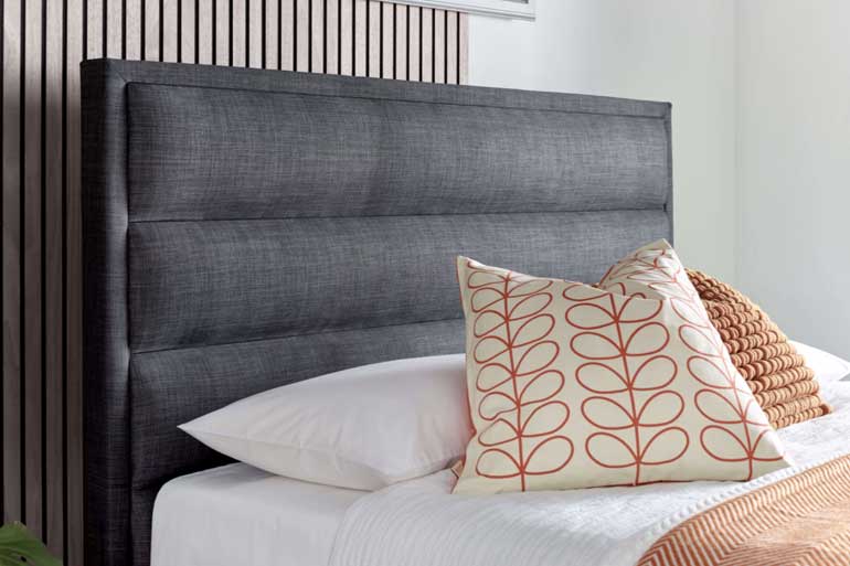 Close-up of Kaydian Kirkby Ottoman Bed in Slate with orange pillows and throw.
