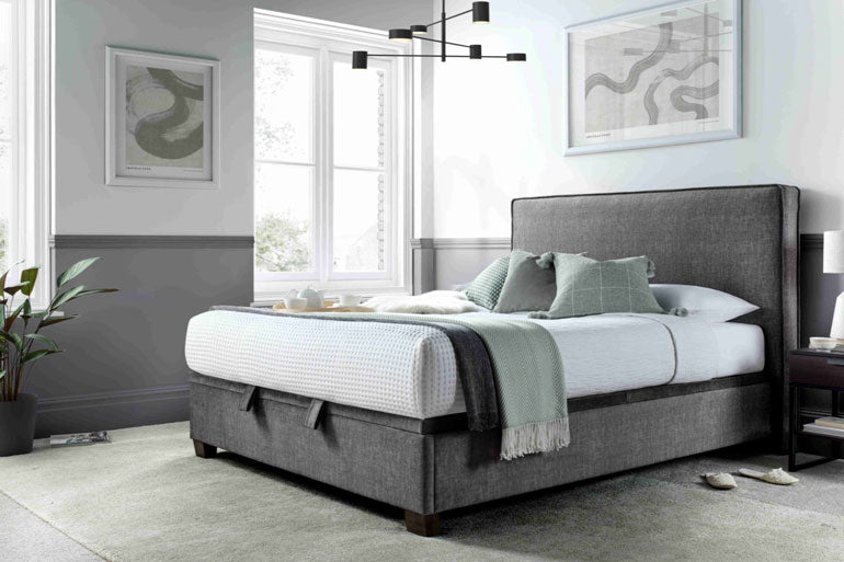 Kaydian Newton Ottoman Bed in Vogue Grey with white bedding in bedroom setting.