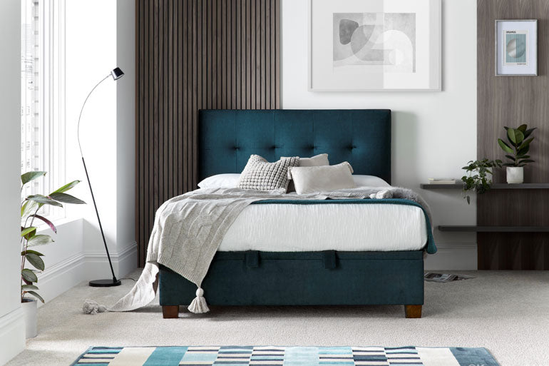 Kaydian Walkworth Ottoman Bed in Ocean Blue and a storage space beneath, in a furnished room setting.