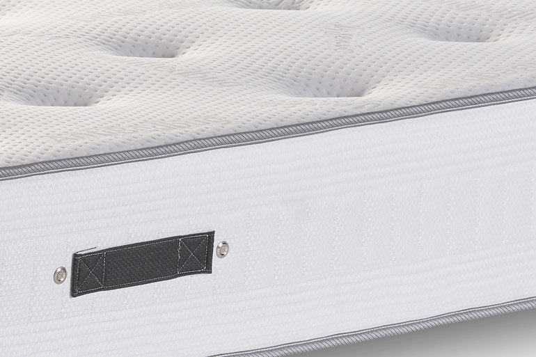 Close-up of a mattress with a brand label on a light gray background