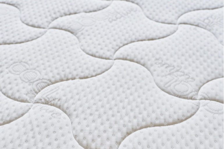 Close-up of a textured white mattress pad with wavy pattern