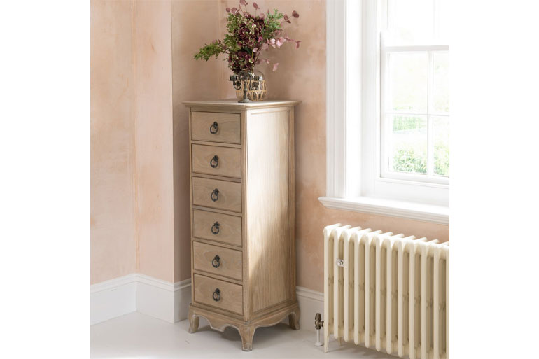 Willis & Gambier Camille 6 Drawer narrow wooden cabinet against a wall with a window and radiator in the background.