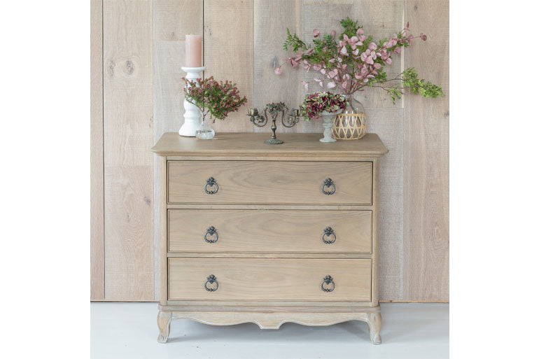 Willis & Gambier Camille Chest Of Drawers with decorative items against a wooden wall.