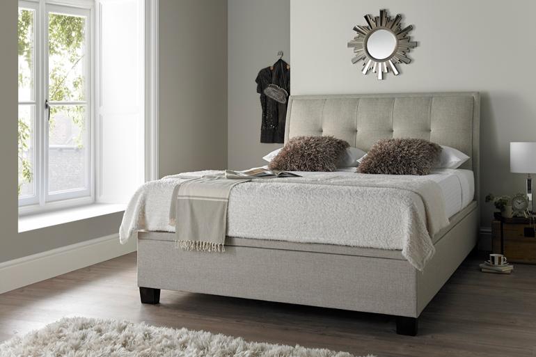 Kaydian Accent Oatmeal Ottoman Bed in white bedroom and wooden floor.
