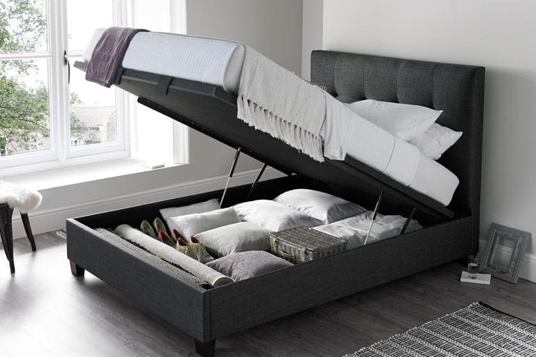 Kaydian Walkworth Ottoman Bed in Slate with the storage compartment open showing bedding inside.