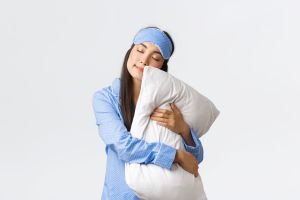 A young woman in blue pajamas hugging a pillow