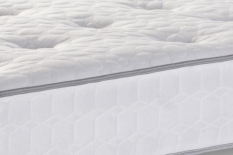 Close-up of a white quilted mattress cover with a gray border.