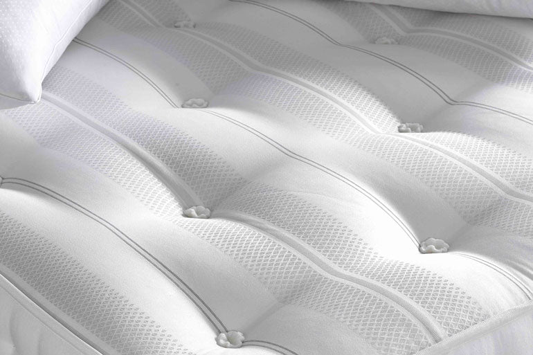 Close-up of a white mattress with tufted design