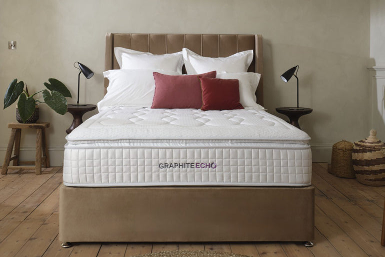 White mattress with 'Graphiteecho' branding on a brown bed frame in a bedroom setting.
