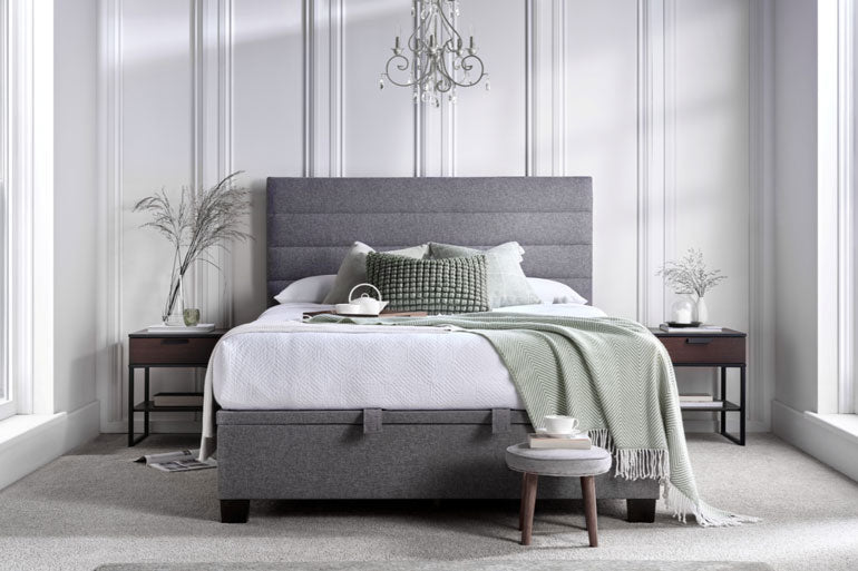 Kaydian Appleford Ottoman Bed in Marbella Grey in a stylish bedroom with white walls and decorative elements.