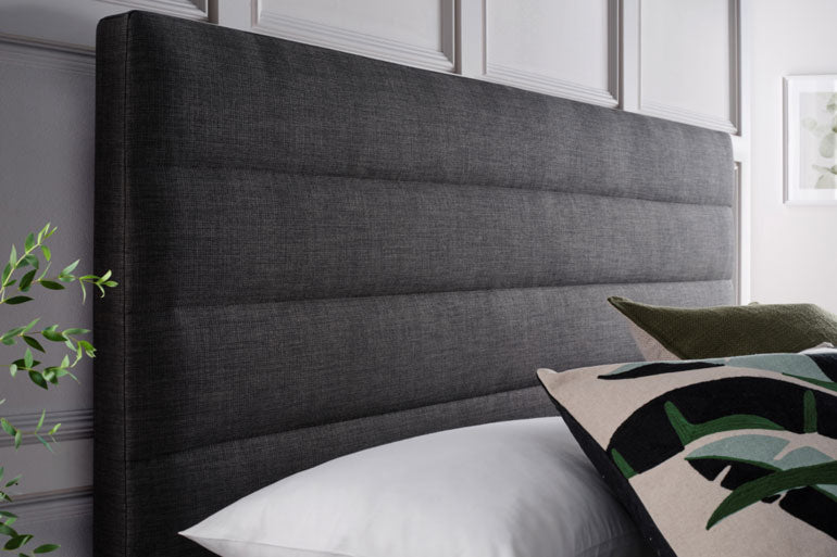 Close-up of Kaydian Appleford Ottoman headboard Slate Grey in a bedroom setting with pillows.