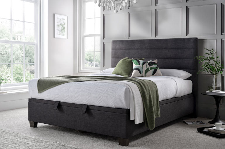 Bedroom with a Kaydian Appleford Ottoman bed in slate, white bedding, and decorative pillows.