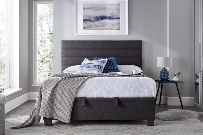 Kaydian Appleford Ottoman Bed in Slate with white bedding in a bedroom setting.