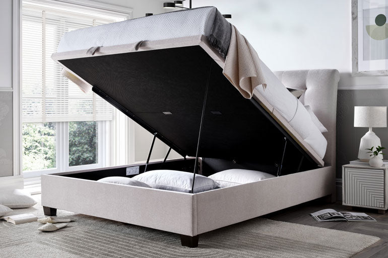Kaydian Ashbrooke Ottoman bed in Maskat Clay with storage compartment open in a bedroom setting.