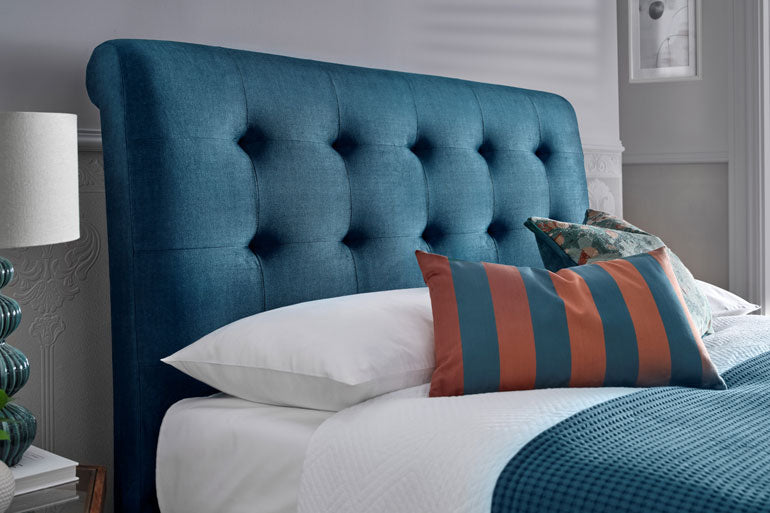 Close-up of Kaydian Ashbrooke Ottoman headboard with pillows on a bed in a bedroom setting