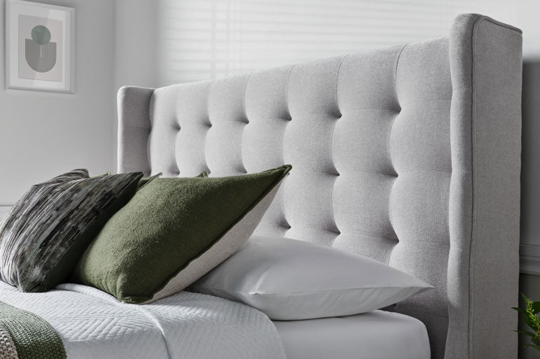 Brunstock upholstered headboard with decorative pillows on a bed in a bedroom setting.