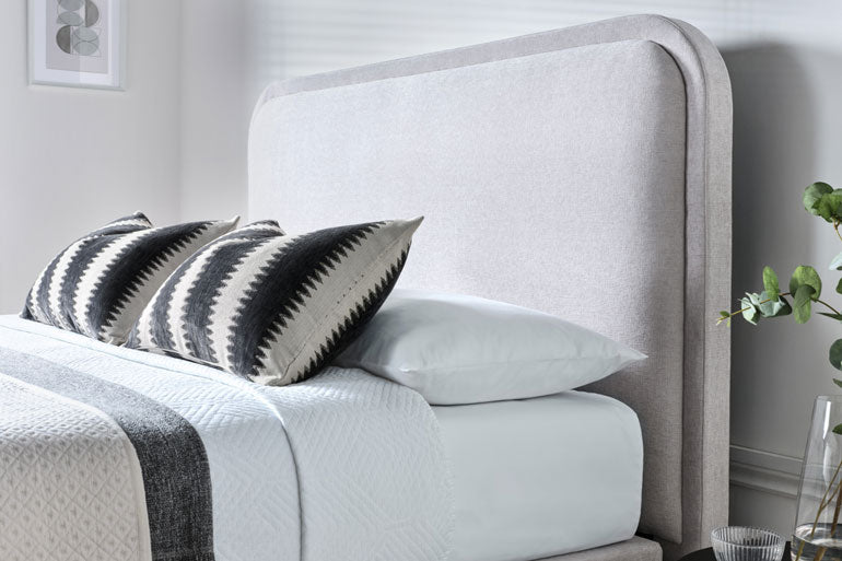 Neatly made bed with decorative pillows and a Clitheroe Ottoman Headboard.
