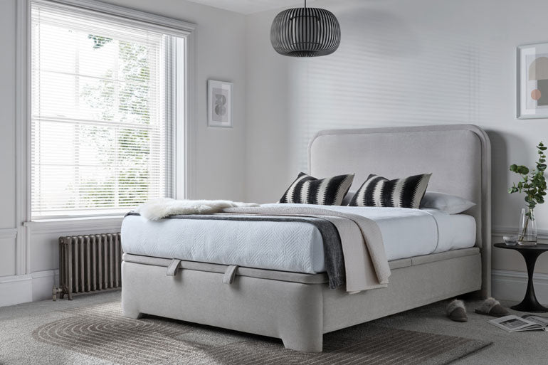 Kaydian Clitheroe Ottoman bed in a modern bedroom with large window and decorative elements.
