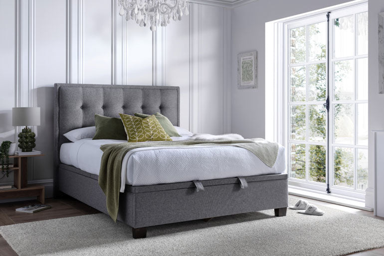 Kaydian Falfield Ottoman bed in Marbella Grey with white bedding and green throw in a bright bedroom.