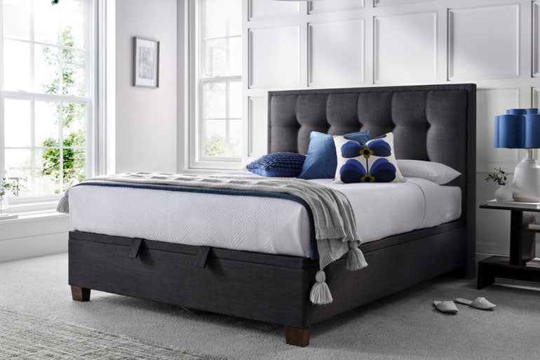 Kaydian Falfield Ottoman bed in Slate with white bedding and blue pillows in a bright bedroom.