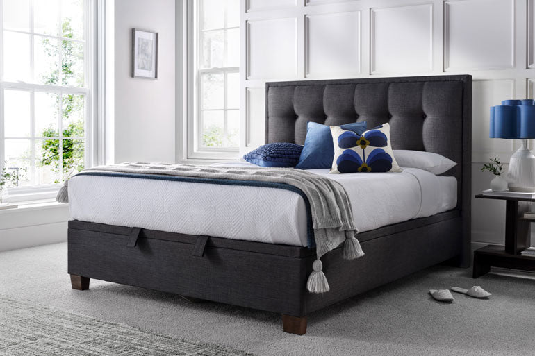 Kaydian Falfield Ottoman bed in Slate with white bedding and blue pillows in a bright bedroom.