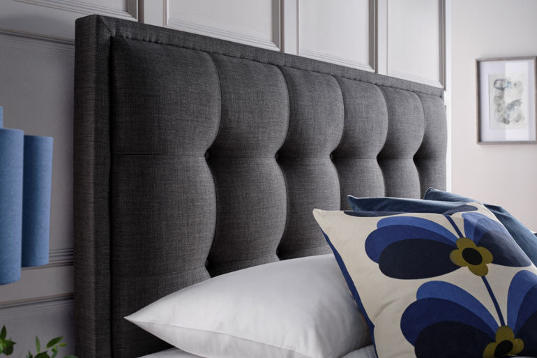Close-up of Kaydian Falfield Ottoman headboard in slate with decorative pillows.