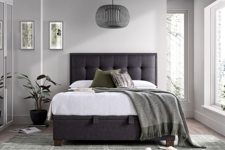 Bedroom with a Kaydian Falfield Ottoman bed in Slate, white bedding, and decorative pillows.