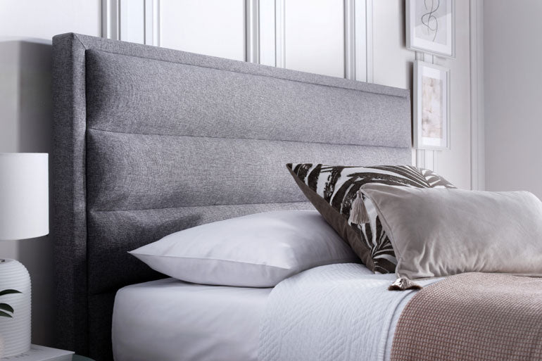 Kaydian Kirkland Ottoman headboard with pillows on a bed in a bedroom setting.