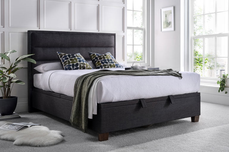 Bedroom with a Kaydian Kirkland Ottoman Bed in slate, white bedding, and decorative pillows.