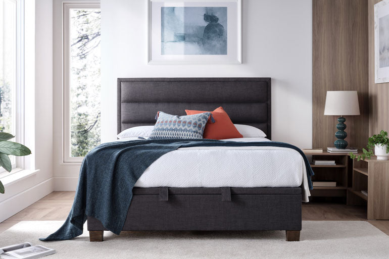 Bedroom with a Kaydian Kirkland Ottoman Bed in Slate, white bedding, and decorative pillows.