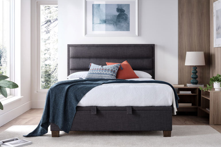Bedroom with a Kaydian Kirkland Ottoman Bed in Slate featuring colorful pillows in bedroom setting.