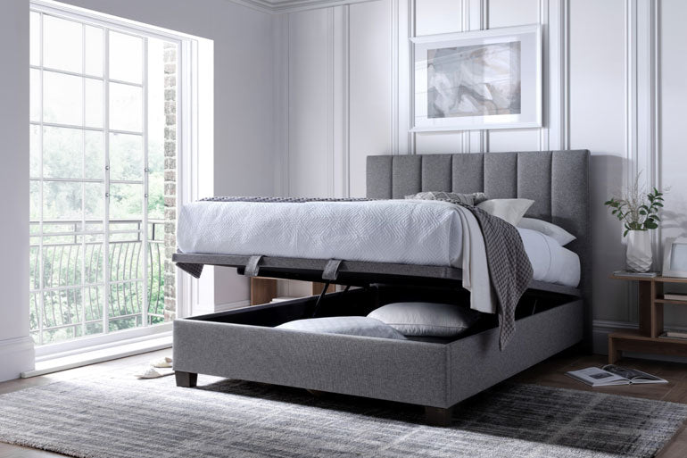Kaydian Medlam Ottoman Bed in Marbella Grey with the storage slightly open in a modern bedroom.
