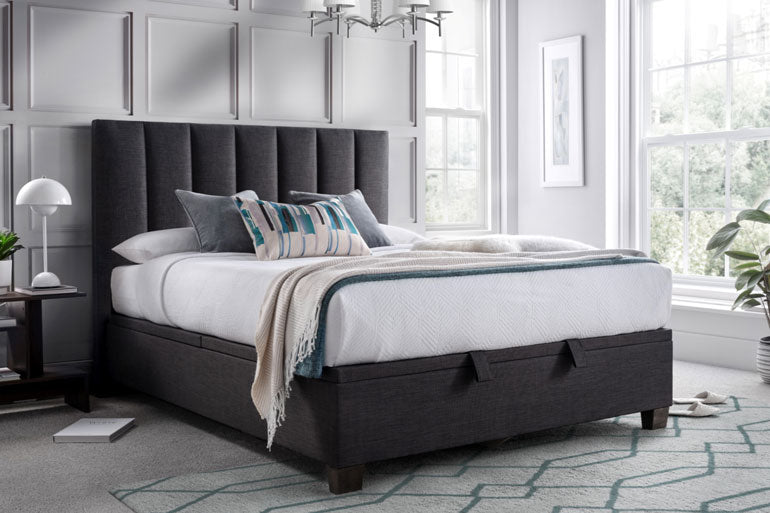 Bedroom with a Kaydian Medlam Ottoman Bed in Slate with white bedding, and decorative pillows.