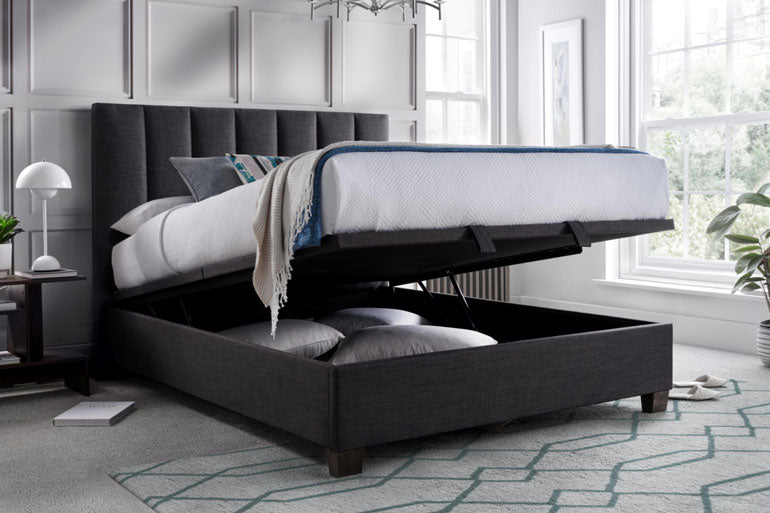 Grey upholstered bed with storage compartment in a bedroom setting
