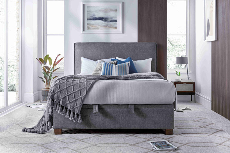 A Kaydian Newton Ottoman Bed in Vogue Grey with a high headboard, placed in a stylish bedroom setting.