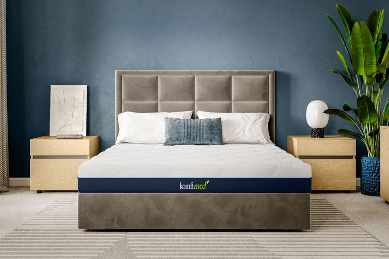 Komfi Med Pro Mattress on a bed in a bedroom with a blue wall and plant.