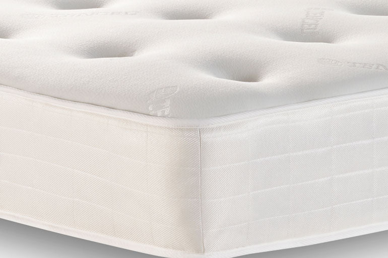Close-up of a white mattress with quilted surface and visible stitching.
