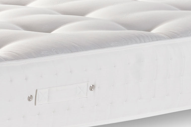 Close-up of a white mattress with quilted surface and visible brand logo.