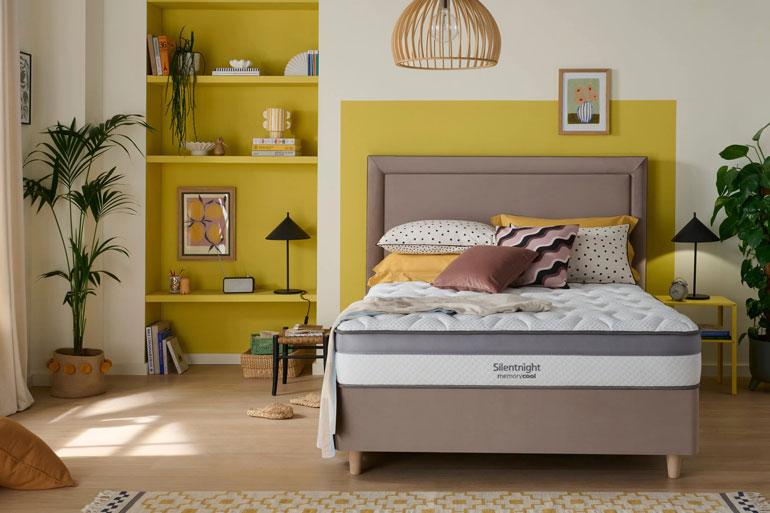 Bedroom with a bed featuring a Silentnight Memory Cool 1000 Mattress, yellow walls, and decorative elements.
