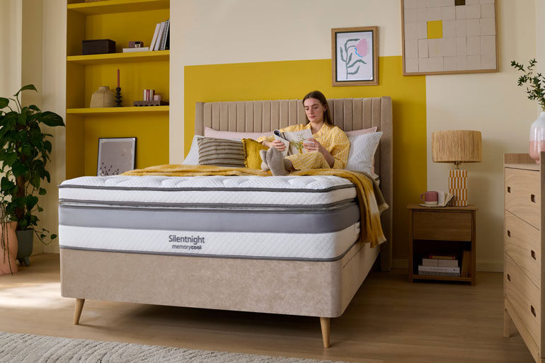 Bedroom setting with a woman sat on a Silentnight Memory Cool 3000 Mattress