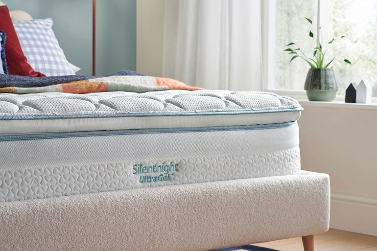 Close-up of Silentnight mattress in a bedroom setting with pillows and decor.