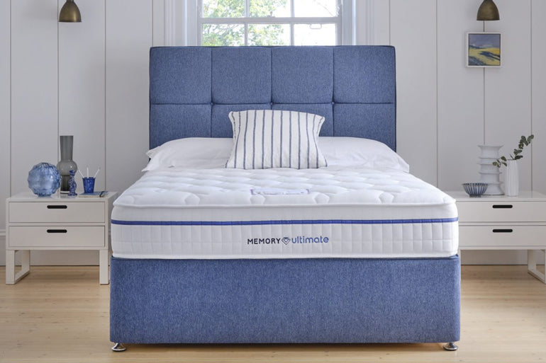 Blue upholstered bed with 'Memory Ultimate' mattress in a bedroom setting