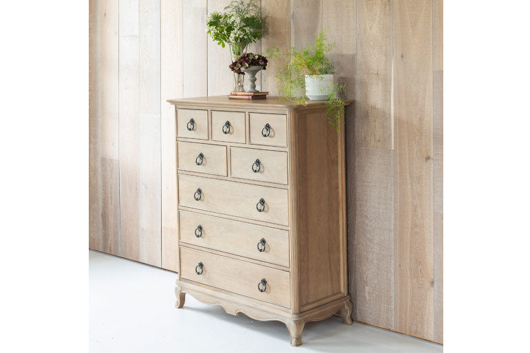Willis & Gambier Wooden 8 Drawer chest of drawers with decorative items against a wooden paneled wall.