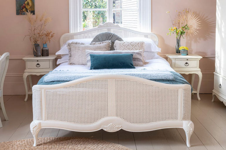 White rattan bed with bedsides and decorative pillows in a bedroom setting