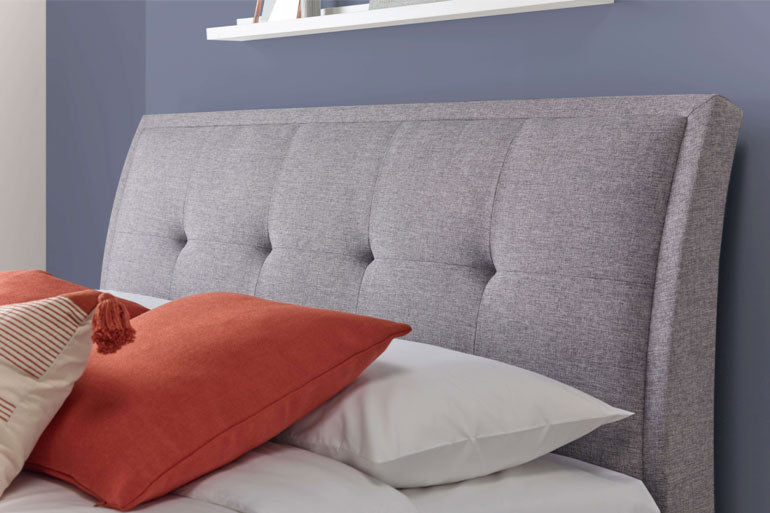 Close-up of Accent Ottoman Headboard in Marbella Grey with orange pillow.