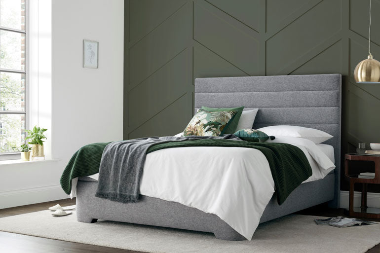 A Kaydian Appleby Ottoman Bed displayed in a bedroom setting with white bedding and pillows on top.